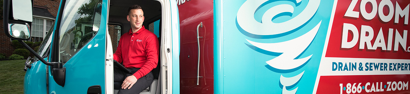 A Zoom Drain technician in the driver's seat of a Zoom Drain truck