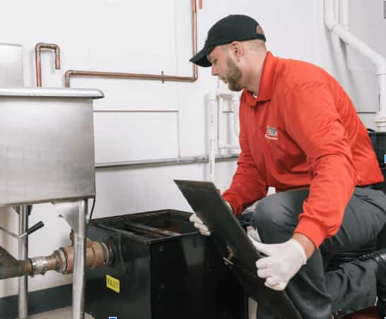 A Zoom Drain specialist inspects a restaurant grease trap